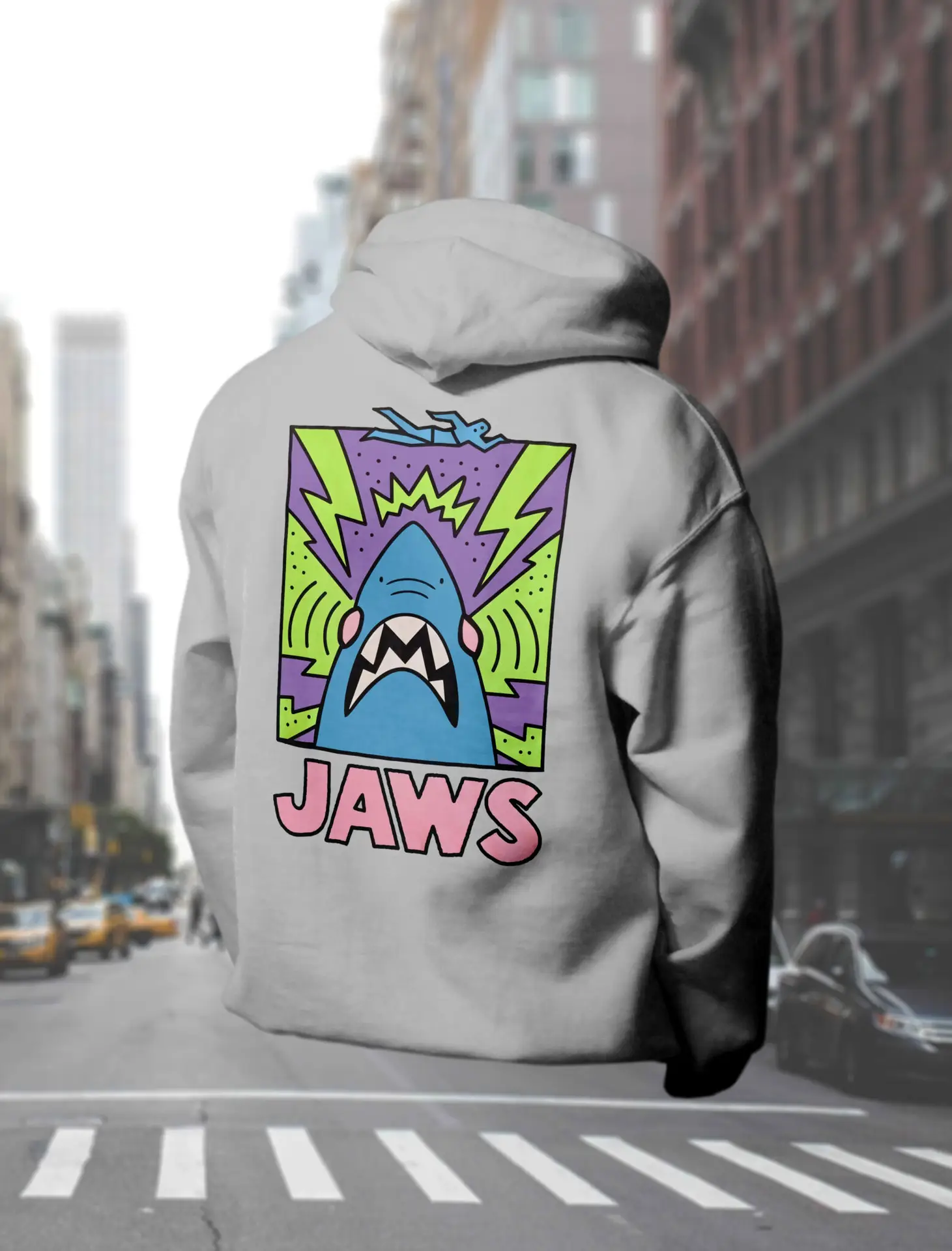 A rizzed out hoodie hovering above the street of new york as a mockup for a double layered hooded sweatshirt with a dope 90s vibe JAWS print on the back in purple, lime green, pink and blue.